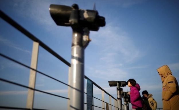 A girl looks toward the North through a pair of binoculars near the demilitarized zone separating the two Koreas in Paju, South Korea, January 3, 2018.