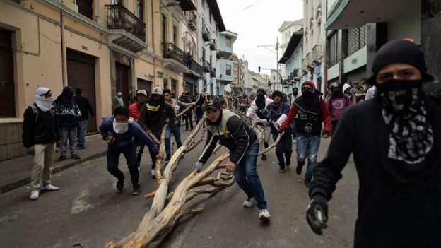 Manifestantes llevando un tronco seco por las calles de Quito.