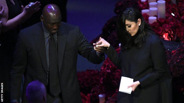 Basketball legend Michael Jordan (left) helps Vanessa Bryant (right) down from the stage after she gives a speech at Kobe and Gianna Bryant's memorial service