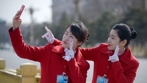Mujeres chinas posando para un selfie con guantes.