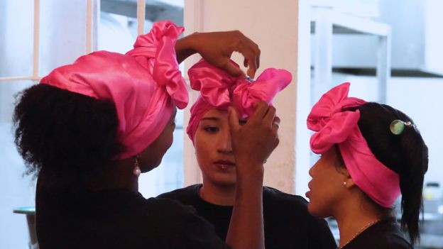 Mujeres que atienden en el restaurante, arreglándose los lazos fucsias que se ponen en la cabeza.