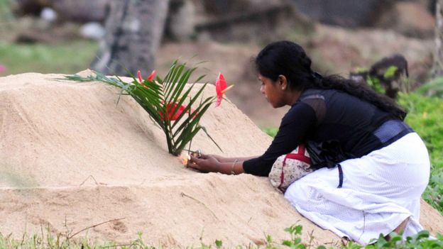 Mujer colocando flores en una tumba tras el tsunami de Asia en 2004