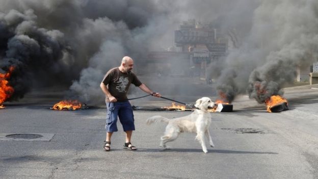 A protester and his dog stand in front of flames