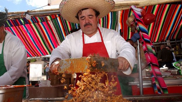 cocinero mexicano con sombrero charro está cortando carne en la calle