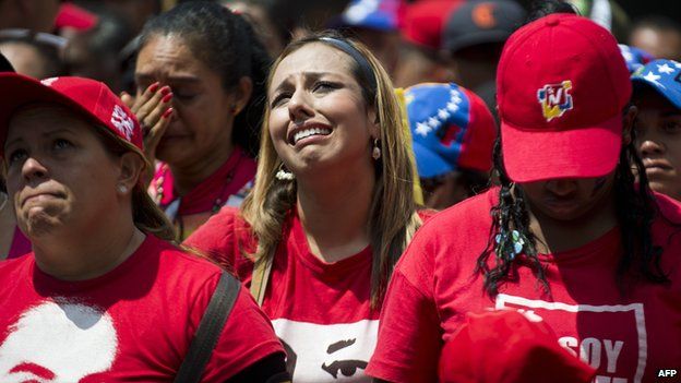 People cry as the coffin of Venezuelan President Hugo Chavez passes by them in Caracas on 15 March 2013