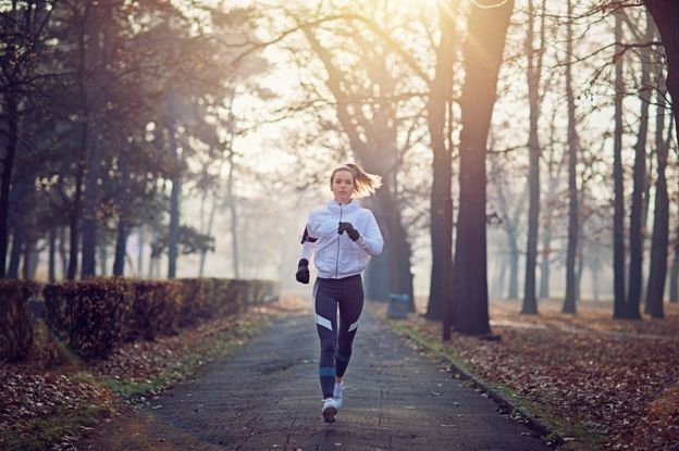 Woman running in a park, wearing headphones