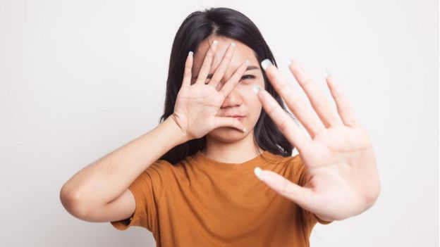 Mujer tapándose la cara con las manos.