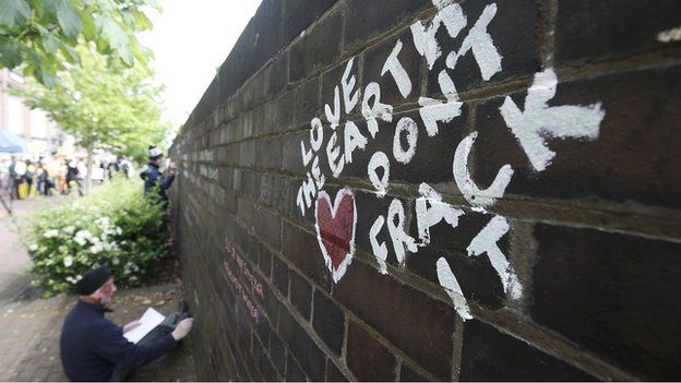 An anti-fracking protester writes messages on a wall in Lancashire