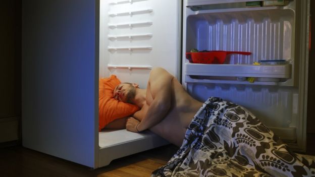 Un hombre durmiendo en una refrigeradora.