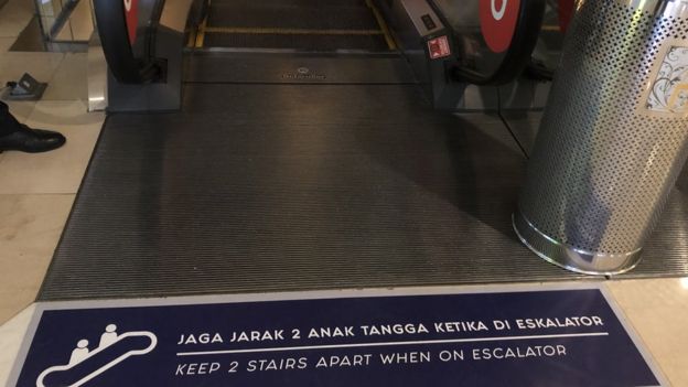 Pengunjung harus berjarak dua anak tangga satu sama lain untuk menggunakan eskalator di Grand Indonesia.
