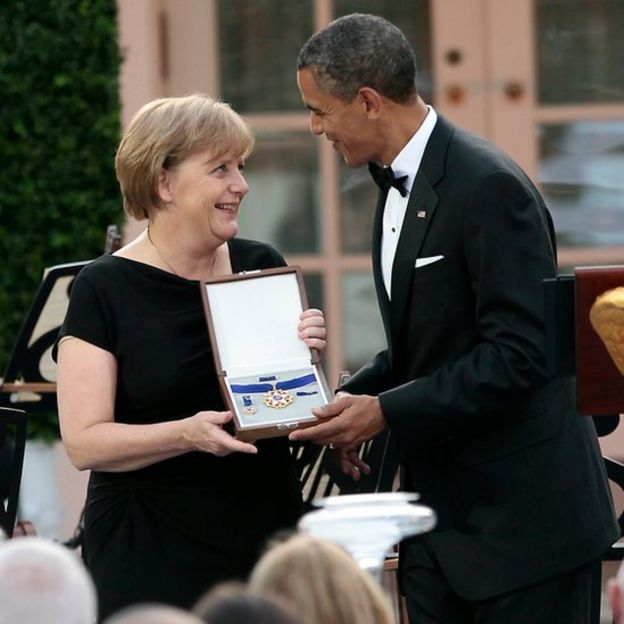 Angela Merkel junto a Barack Obama, ambos sonriendo.