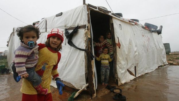 Syrian refugee children stand near their temporary shelter at a refugee camp in Lebanon
