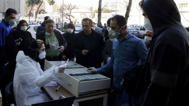 A health worker registers people waiting for a Covid-19 test outside a lab in Tehran, Iran (9 March 2020)