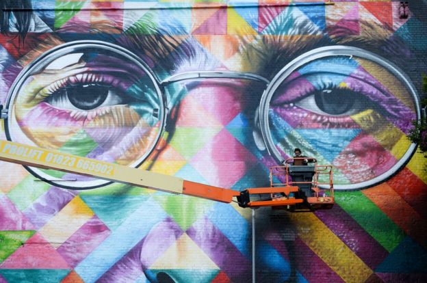 فنان جداري يرسم صورة لجون لينون، أحد مؤسسي البيتلز البريطانية الشهيرة، على حائط كجزء من مهرجان آبفيست للفن الجداري في مدينة بريستول.