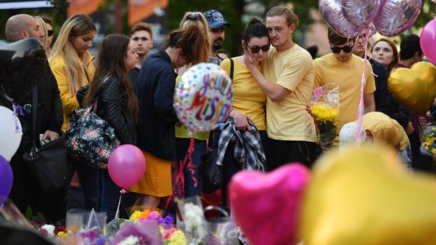 Un grupo de personas colocan flores y globos en memoria de las víctimas del atentado en el Manchester Arena.