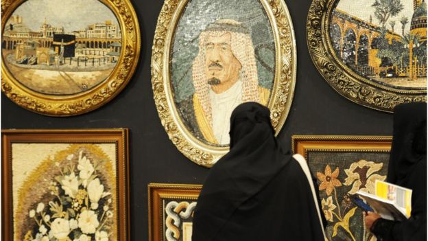 A Saudi woman looks at a portrait of the Saudi King during an interior design fair in the Red Sea city of Jeddah, 8 November 2017