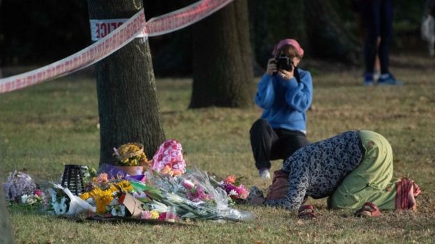 Una mujer reza ante las flores dejadas como homenaje a las víctimas de la mezquita.