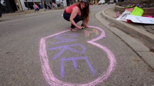 A woman rights "I care" in chalk