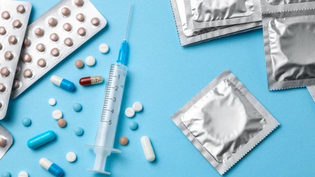 Diversos métodos contraceptivos sobre a mesa, como pílulas e camisinhas