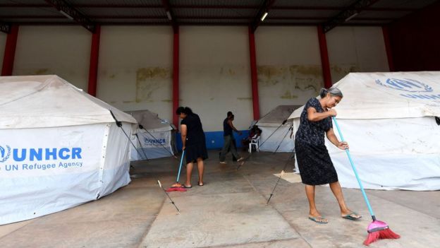 Mulheres varrem o chão em acampamento para venezuelanos no Brasil