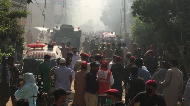 Ambulances and fire brigade vehicles gather at the site of a passenger plane crash in a residential area near an airport in Karachi