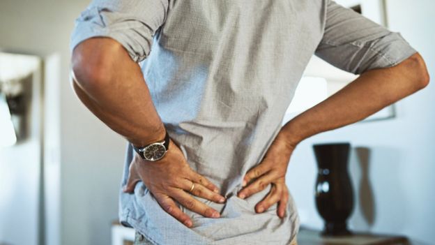 Un hombre con las manos en la zona lumbar.