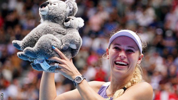 Caroline Wozniacki poses on court with a toy koala bear after losing to Ons Jabeur at the Australian Open