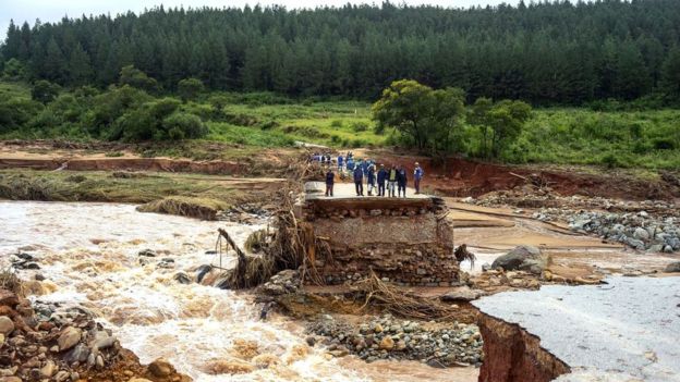 Grupo de personas sobre carretera destruida en Zimbabue.