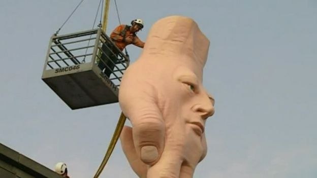 Homem em guindaste ajudando a erguer obra de arte