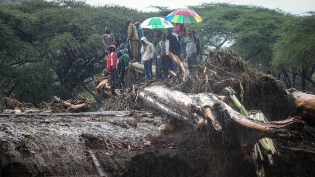 People stand on debris blocking a highway on a bridge after the River Muruny burst its banks in West Poko, Kenya - November 2019