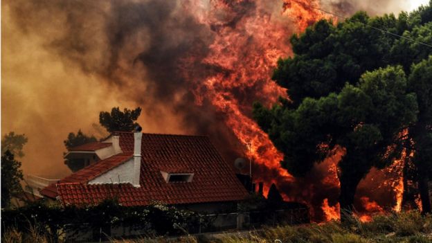 A house is threatened by a huge blaze during a wildfire in Kineta, near Athens, on July 23, 2018