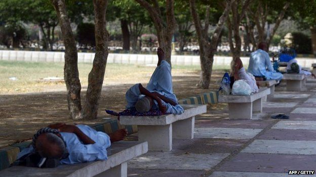 Pakistani men rest in the shade of trees