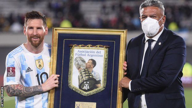 Lionel Messi (left) is presented with a recognition of his 80 goals by the president of the Argentina football association (right)