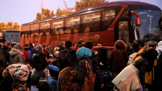 Refugees and migrants wait to board buses that will transfer them to the mainland following their arrival on a passenger ferry from the island of Lesbos at the port of Piraeus, 22 January 2020