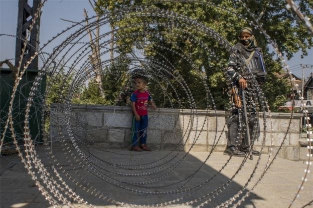 A Kashmir child look towards his parents after he was helped by Indian paramilitary trooper to cross the concertina razor wire laid by Indian government forces during curfew like restrictions, on September 10, 2019 in Srinagar