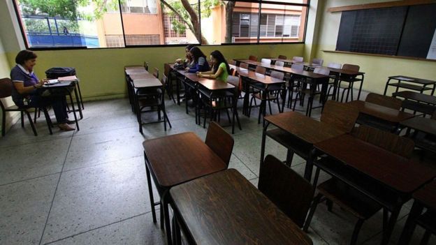 Sala de aula vazia, com apenas a professora e três alunas