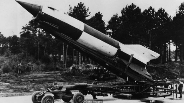 Foto preto e branca mostra foguete em pátio
