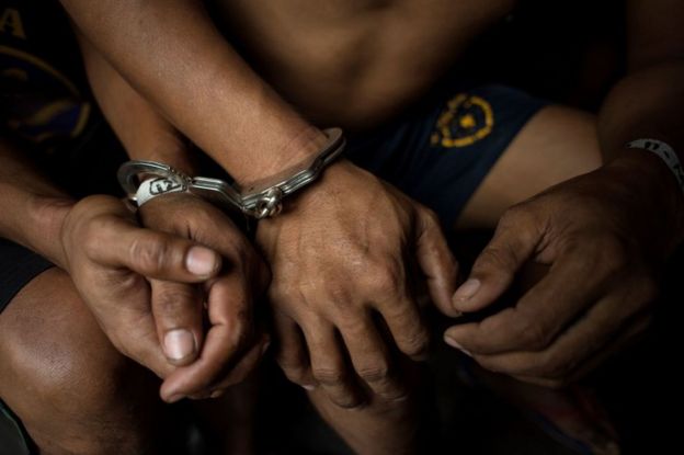 Handcuffed male residents are rounded up for verification after police officers conducted a large scale anti-drug raid at a slum community in Manila on 20 July 2017