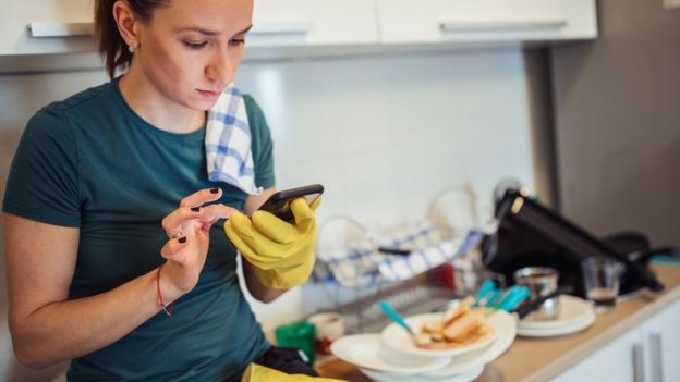 Mujer con telefono en la cocina