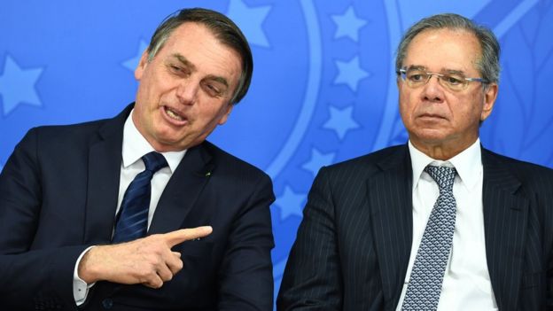 Jair Bolsonaro aponta para Paulo Guedes durante cerimônia de posse do novo presidente do BNDES, em 16 de junho de 2019, em Brasília