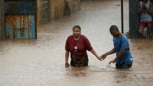 Two people wade through rising floodwaters in Pemba, Mozambique after Cyclone Kenneth struck the African nation