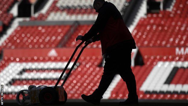 Ground staff at Old Trafford work to prepare the pitch