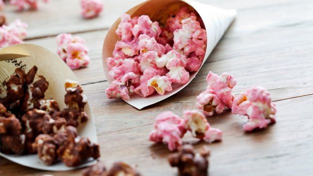 Strawberry & chocolate popcorn spilling onto wooden surface