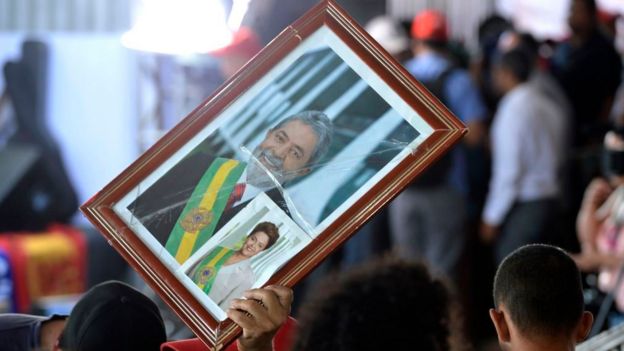 Em protesto, apoiador dos governos petistas levanta quadro com foto de Lula e Dilma com faixas presidenciais