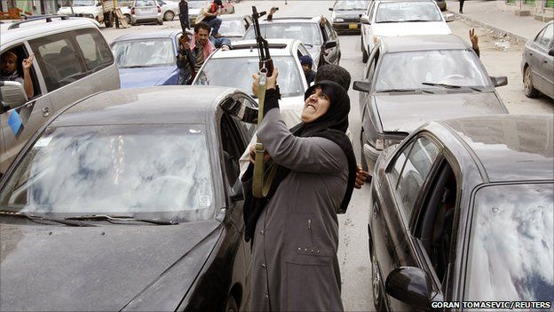 A woman rebel fighter supporter shoots an AK-47 rifle as she reacts to the news of the withdrawal of Libyan leader Colonel Gaddafi's forces from Benghazi, 19 March