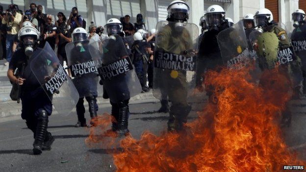 A petrol bomb explodes beside riot police officers near Syntagma square during a 24-hour labour strike in Athens, 26 September 2012
