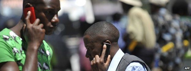People walk while speaking on the phone on 1 October 2012 in Nairobi, Kenya