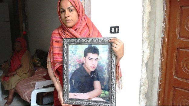 Tunisian Aida Dechich holds up a framed photograph of her brother Sofien Dechich