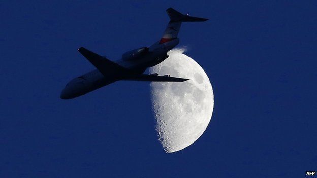 A commercial plane flying in front of the moon