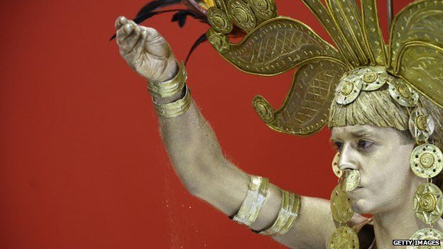 A man dressed as the mythic figure of El Dorado sprinkles gold dust